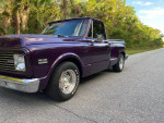Custom modified 1971 Chevy C10 Shortbed Stepside pickup truck in purple color parked on a scenic road.