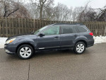 2011 Subaru Outback in gray, reliable AWD vehicle with 79,000 miles, parked on a wet street.