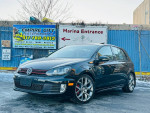 2013 Volkswagen GTI Driver's Edition 2.0T in black with alloy wheels parked near a marina entrance