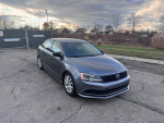 2015 Volkswagen Jetta SE in gray color, parked on asphalt with cloudy sky, showcasing alloy wheels and clean exterior.