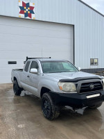 2005 Toyota Tacoma pickup truck with new tires and front light bar, parked in front of a garage