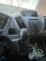 Interior view of a 2016 Ford Transit 350 Van showing dashboard and gear shift.