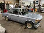 1972 BMW 2002 Tii in gray, showcasing sleek design and classic features, located in a garage.