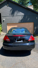 2007 Honda Accord EX-L Coupe parked in front of a garage, showcasing its rear view and clean design.