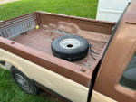 Open bed of a 1987 Ford F250 pickup showing a spare tire and clean interior.