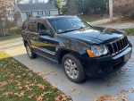 2008 Jeep Grand Cherokee Limited with 188,500 miles, standing on driveway with autumn leaves.