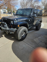 2012 Jeep Rubicon with new tires and accessories, parked on a driveway