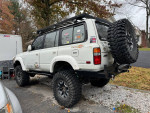 Toyota Landcruiser with modifications including lift, off-road tires, and roof rack parked outdoors