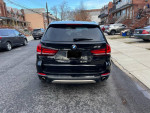 Rear view of a 2016 BMW X5 parked on a residential street, showcasing its sleek design and clean exterior.
