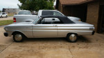 1964 Ford Falcon convertible in silver with a black power top parked in a driveway.