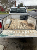 View of the truck bed in a 2004 Ford F350 diesel, featuring some rust and a dirty floor.