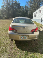 Rear view of a 2005 Toyota Avalon parked on grass, showing its licensed plate and slight damage.