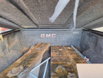Interior of 2008 GMC Sierra truck bed with wooden planks and GMC logo