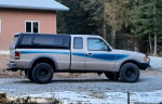 1993 Ford Ranger 4x4 truck with blue graphics, parked in a rural setting, showcasing its condition and rugged design.