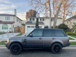 2006 Land Rover Range Rover parked in front of a house, showcasing its sleek design and black wheels.