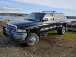 1995 Dodge 3500 dually truck parked near a body of water, showcasing its rugged features and off-road capability.