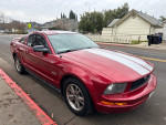 2005 Ford Mustang Deluxe Coupe in red parked on the street, clean interior and exterior, 149,000 miles, with a manual 5-speed transmission.