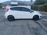 2015 Ford Fiesta with 83,000 miles, white color, manual transmission and good tires, parked in a lot.