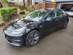 2018 Tesla Model 3 Mid Range RWD in great condition parked outdoors with new tires and a scenic background.
