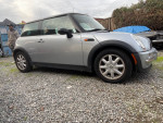 2004 MINI Cooper in silver, parked on gravel, showing the side view and missing brake light.