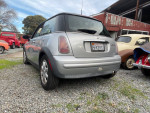 2004 MINI Cooper parked with other vintage cars, showing its distinctive rear design and silver color.