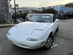 1994 Mazda Miata MX-5 parked on a street, showcasing its sporty design and clean body.