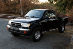 1998 Toyota Tacoma SR5 4WD extended cab in black with 60,000 miles, parked on a gravel road.