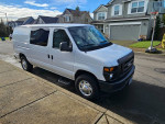 2012 Ford E-250 work van parked on the street, featuring storage cabinets and a clean exterior