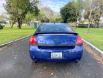 Rear view of a 2006 Chevrolet Impala SS in blue, parked in a green park setting.