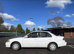 2001 Toyota Corolla CE sedan parked under a clear blue sky, showing its reliable design and features.