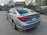 2015 Hyundai Sonata with 130,000 miles, parked in a residential area, showing rear view and body condition.