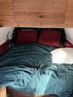 Cozy interior of a 2003 camper van with a bed and wooden accents, showcasing its spacious design.