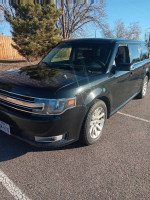 2013 Ford Flex SEL in black metallic, featuring three rows of seating and winter tires, parked on a road.