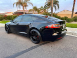 2018 Tesla Model S P100D in black, fully loaded, parked on a residential street with palm trees.