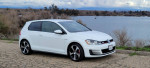 2015 Volkswagen GTI in white parked near a body of water, highlighting clean condition and stock features.