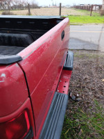 Close-up of a red 1998 Dodge Ram truck showing bed and body condition with minor dents.