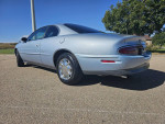 1997 Buick Riviera Supercharged coupe with chrome wheels parked on a sunny day