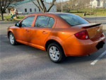 2005 Chevrolet Cobalt LS in orange, featuring alloy wheels and a sunroof, parked in a scenic area.