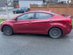 2012 Hyundai Elantra in good condition with winter tires, viewed from the side, parked on a street.