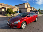 2013 Volvo S60 T5 sedan in red parked in front of a house, showcasing its sleek design and excellent condition.