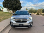 Front view of a 2020 Honda Pilot Touring FWD parked in a residential area, showcasing its sleek design.
