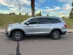 2020 Honda Pilot Touring FWD in silver, parked on a road with scenic background, featuring stylish design and low mileage.