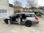 2005 Subaru Outback with opened doors, showcasing interior and exterior, parked in driveway.