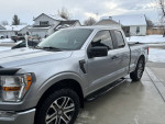 Silver Ford F-150 in excellent condition with weather tech accessories, parked in a snowy residential area