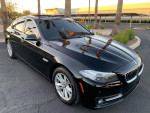 2015 BMW 5 Series 528i in black, showcasing sleek design and modern features with palm trees in background.