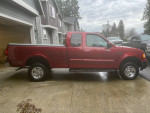 1999 Ford F-150 XLT 4WD in red, well-maintained, parked on driveway, showing side view.