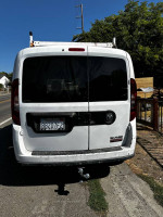 Rear view of a 2006 Dodge Promaster City van parked on the street, showcasing its work-friendly design and utility.