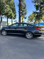 2015 Hyundai Sonata Eco in black, parked under trees, showcasing sleek design and alloy wheels.