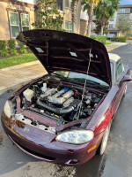 Photo of a 2000 Mazda Miata hood open, showcasing its clean engine bay and well-maintained components.