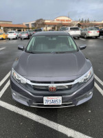 Front view of a 2016 Honda Civic EX sedan with low mileage, parked in a lot, showcasing its sleek design.